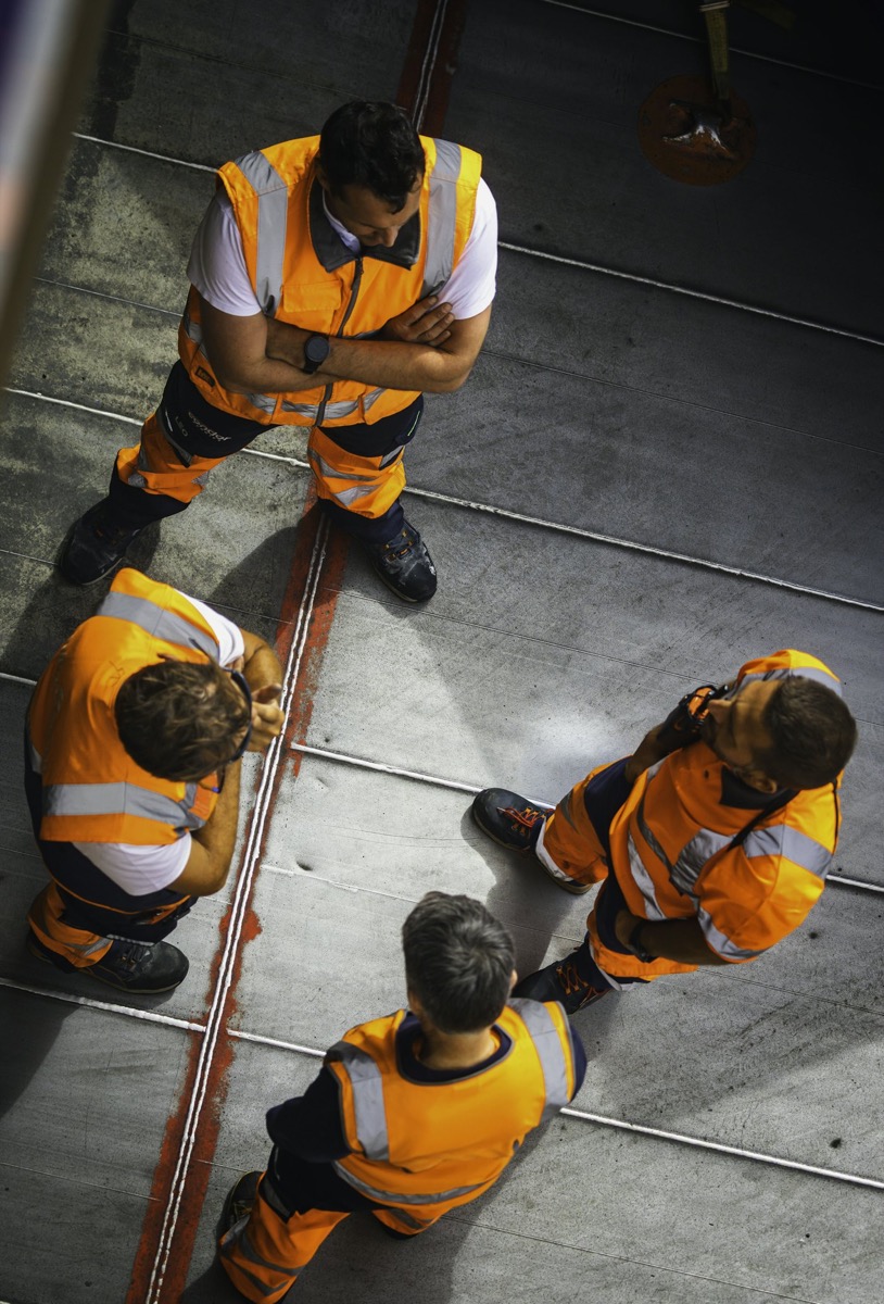 Equipo de trabajo con ropa de alta visibilidad en una nave industrial